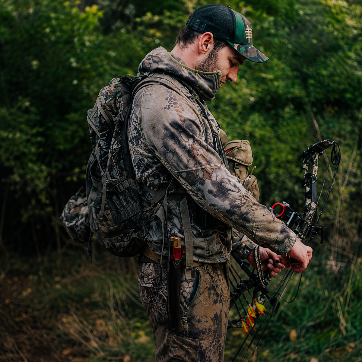 
Hunter in camouflage adjusting a compound bow in a forest